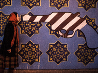 Symbolic portrait of young woman giving a kiss to a gun painted in the colors of USA on old closed US embassy in Tehran.

 (