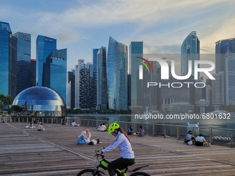 People relax on an outdoor deck as the sun sets in Marina Bay in Singapore on Monday, 14 June, 2021. Singapore begins to roll back a month o...