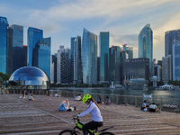 People relax on an outdoor deck as the sun sets in Marina Bay in Singapore on Monday, 14 June, 2021. Singapore begins to roll back a month o...