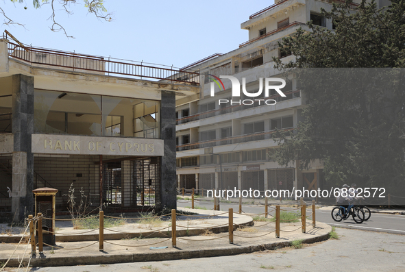 Tourists cycle past an abandoned Bank of Cyprus building, fenced off by the Turkish military since 1974, in the abandoned coastal area of Va...