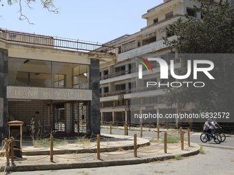 Tourists cycle past an abandoned Bank of Cyprus building, fenced off by the Turkish military since 1974, in the abandoned coastal area of Va...