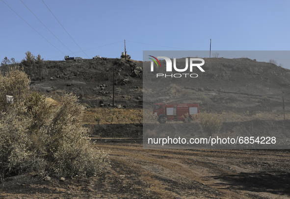 Fire truck rides past the burnt-out area near the village of Eptagonia, in Limassol mountain region. Cyprus, Monday 5 July 2021. The wildfir...