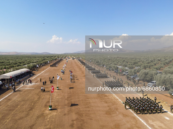 Syrian fighters march in columns, ride dirt bikes and and drive pick-up trucks during a graduation ceremony near the northern city of Afrin...