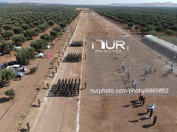 Syrian fighters march in columns, ride dirt bikes and and drive pick-up trucks during a graduation ceremony near the northern city of Afrin...