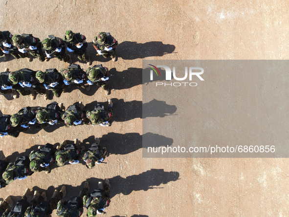 Syrian fighters march in columns, ride dirt bikes and and drive pick-up trucks during a graduation ceremony near the northern city of Afrin...