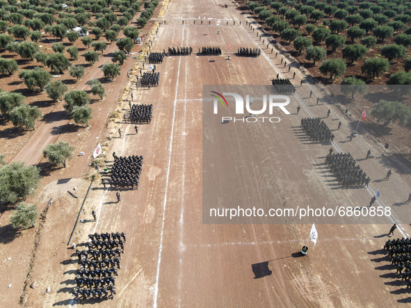 Syrian fighters march in columns, ride dirt bikes and and drive pick-up trucks during a graduation ceremony near the northern city of Afrin...