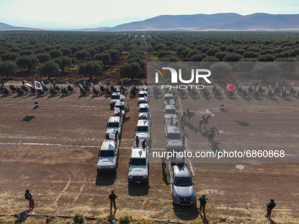 Syrian fighters march in columns, ride dirt bikes and and drive pick-up trucks during a graduation ceremony near the northern city of Afrin...