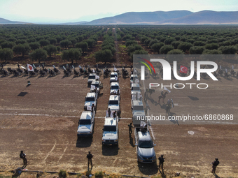 Syrian fighters march in columns, ride dirt bikes and and drive pick-up trucks during a graduation ceremony near the northern city of Afrin...