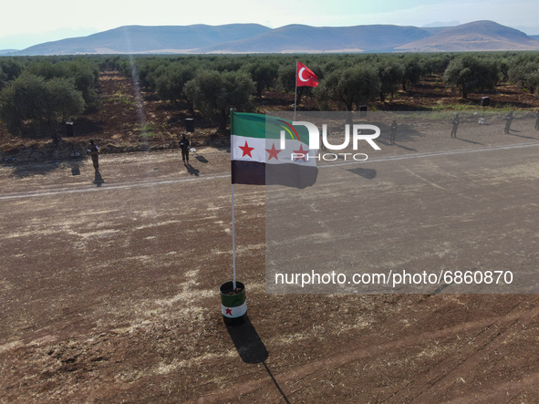 Syrian fighters march in columns, ride dirt bikes and and drive pick-up trucks during a graduation ceremony near the northern city of Afrin...