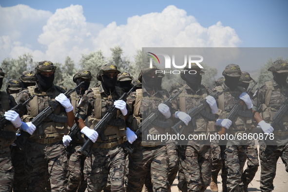 Syrian fighters march in columns, ride dirt bikes and and drive pick-up trucks during a graduation ceremony near the northern city of Afrin...