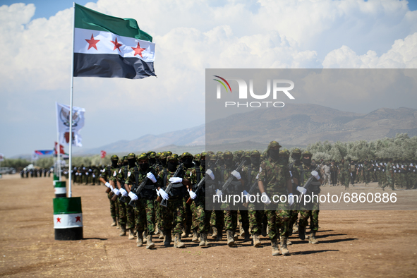 Syrian fighters march in columns, ride dirt bikes and and drive pick-up trucks during a graduation ceremony near the northern city of Afrin...