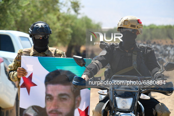 Syrian fighters march in columns, ride dirt bikes and and drive pick-up trucks during a graduation ceremony near the northern city of Afrin...