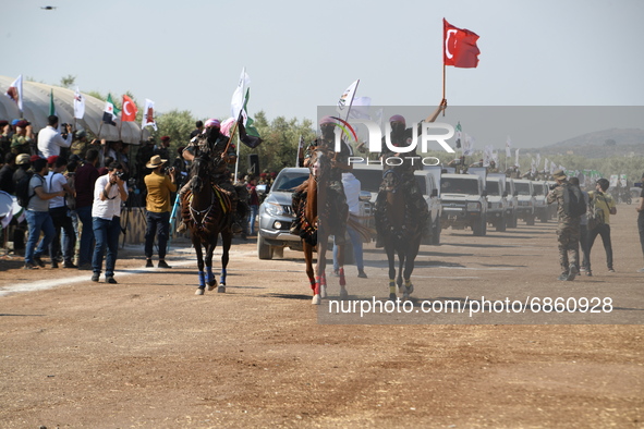 Syrian fighters march in columns, ride dirt bikes and and drive pick-up trucks during a graduation ceremony near the northern city of Afrin...