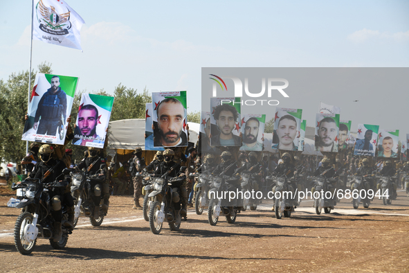 Syrian fighters march in columns, ride dirt bikes and and drive pick-up trucks during a graduation ceremony near the northern city of Afrin...