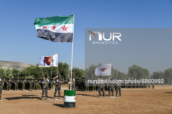 Syrian fighters march in columns, ride dirt bikes and and drive pick-up trucks during a graduation ceremony near the northern city of Afrin...