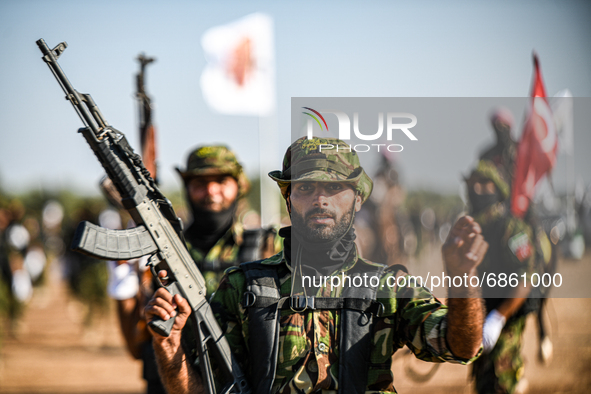 Syrian fighters march in columns, ride dirt bikes and and drive pick-up trucks during a graduation ceremony near the northern city of Afrin...