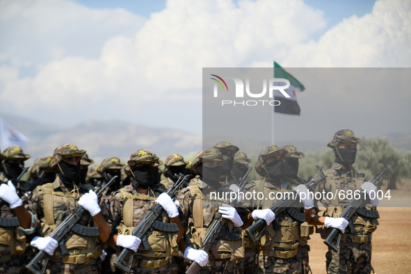 Syrian fighters march in columns, ride dirt bikes and and drive pick-up trucks during a graduation ceremony near the northern city of Afrin...