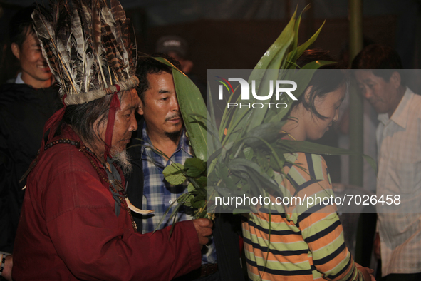 A 90 year-old Lepcha Bomthing (Lepcha priest) wearing a feathered hat chants prayers and uses leaves to bless a village girl during an anima...