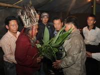A 90 year-old Lepcha Bomthing (Lepcha priest) wearing a feathered hat chants prayers and uses leaves to bless a village man during an animal...