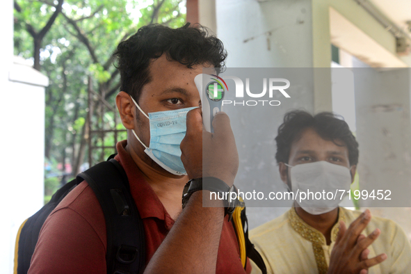 A staff cheek body temperature a students during entry at the residential hall at Dhaka University after reopen their residential halls afte...