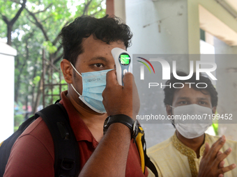 A staff cheek body temperature a students during entry at the residential hall at Dhaka University after reopen their residential halls afte...