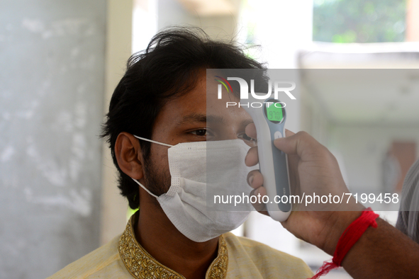 A staff cheek body temperature a students during entry at the residential hall at Dhaka University after reopen their residential halls afte...