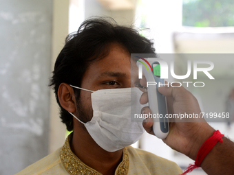 A staff cheek body temperature a students during entry at the residential hall at Dhaka University after reopen their residential halls afte...