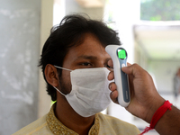 A staff cheek body temperature a students during entry at the residential hall at Dhaka University after reopen their residential halls afte...