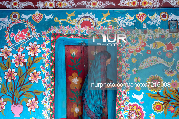 A woman draws traditional motifs on a wall of her house at Tikoil village in Nachole upazila of Chapainawabganj district of Bangladesh. 