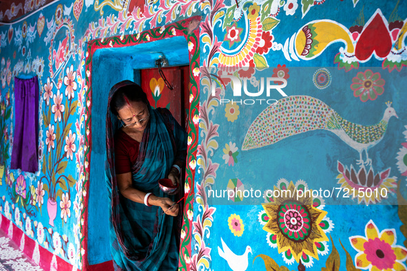 A woman draws traditional motifs on a wall of her house at Tikoil village in Nachole upazila of Chapainawabganj district of Bangladesh. 