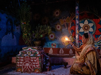 Dekhon Barman prays in her painted house at the dusk time in chapainawabganj in Bangladesh. (