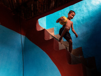 A child carries his football inside a house in alpona village in chapainawabganj, Bangladesh (