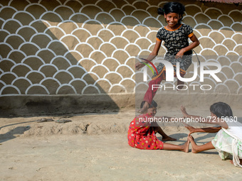 Children play the traditional game in front of a painted wall in alpona village in chapainawabganj, Bangladesh (