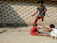 Children play the traditional game in front of a painted wall in alpona village in chapainawabganj, Bangladesh (