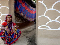 A woman poses in front of her painted house in alpona village in chapainawabganj, Bangladesh. (