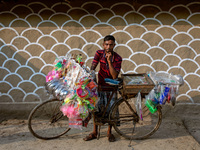 A traditional street vendor poses in front of a painted wall in alpona village in chapainawabganj, Bangladesh (