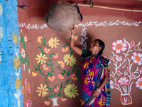 A woman works inside her colorful painted house in alpona village in chapainawabganj, Bangladesh (