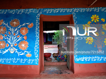 A woman works inside her colorful painted house in alpona village in chapainawabganj, Bangladesh (