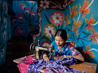 Anita Barman stitches clothes with her sewing machine inside her colourful house as she has been fulfilling her orders to deliver on time. A...