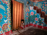 A child poses in front of a colorfully painted house in alpona village in chapainawabganj, Bangladesh. (