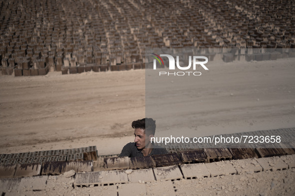 An Afghan refugee labor piles up bricks after removing them from a kiln in a brick factory, in the Borkhar area in the west of the city of I...