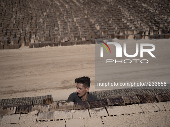 An Afghan refugee labor piles up bricks after removing them from a kiln in a brick factory, in the Borkhar area in the west of the city of I...