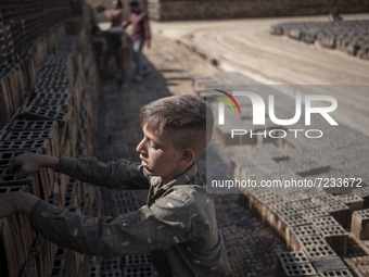 A young Afghan refugee labor piles up bricks after removing them from a kiln in a brick factory, in the Borkhar area in the west of the city...