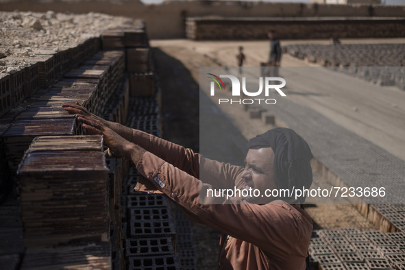 An Afghan refugee labor piles up bricks after removing them from a kiln in a brick factory, in the Borkhar area in the west of the city of I...