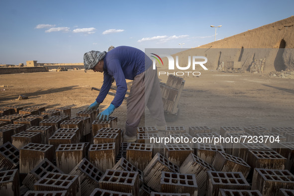 An Afghan refugee labor collects newly made bricks as he works in a brick factory, in the Borkhar area in the west of the city of Isfahan 43...