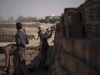 A young Afghan refugee labor piles up bricks after removing them from a kiln in a brick factory, in the Borkhar area in the west of the city...