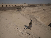 An Afghan refugee labor carrying newly bricks as he walks along an area in a brick factory, in the Borkhar area in the west of the city of I...