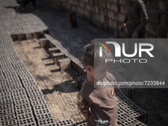 A young Afghan refugee boy stands on newly bricks in a brick factory, in the Borkhar area in the west of the city of Isfahan 439Km (273 Mile...