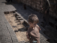 A young Afghan refugee boy stands on newly bricks in a brick factory, in the Borkhar area in the west of the city of Isfahan 439Km (273 Mile...