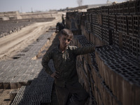 A young Afghan refugee labor looks on as he poses for a photograph while standing next to newly bricks in a brick factory, in the Borkhar ar...